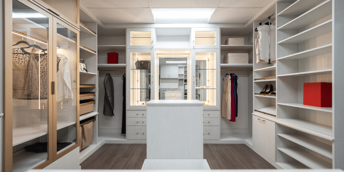 Image of a clean, organized custom closet with built-in island, closet drawers and shelves, and hanging sections.