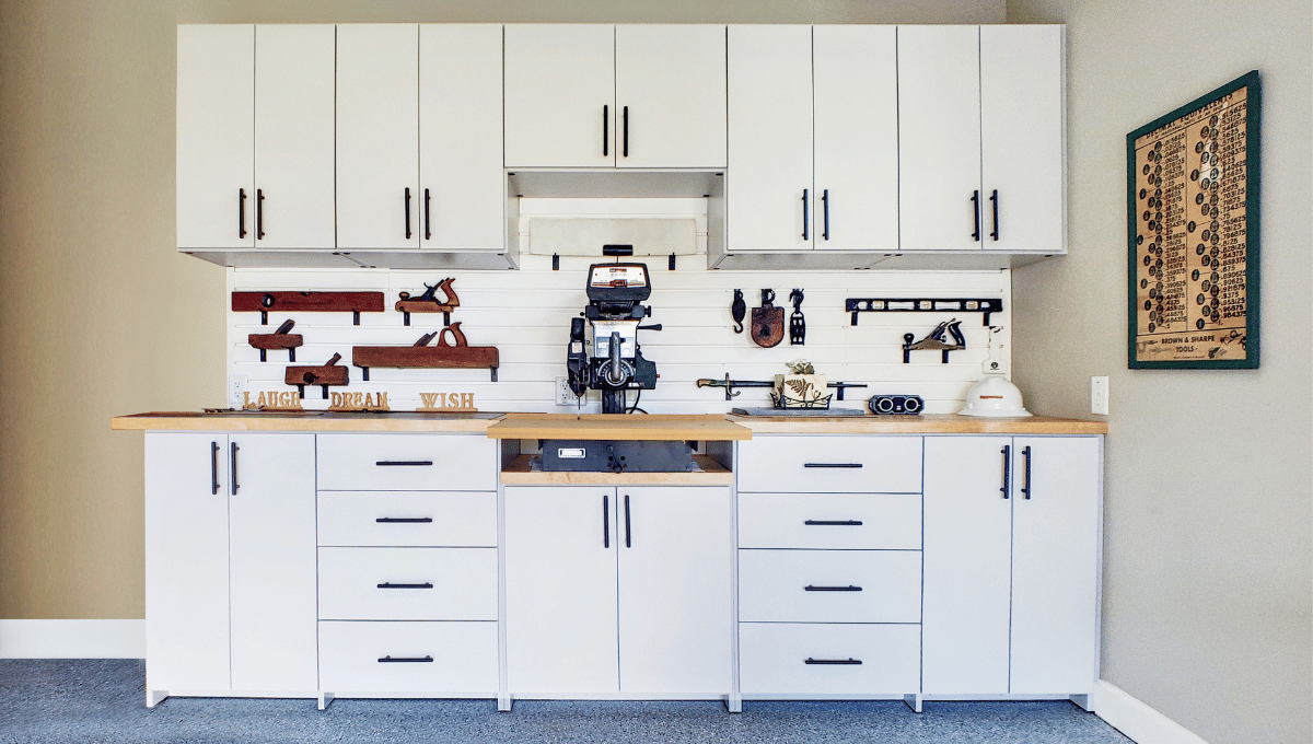 Custom garage cabinets in white with warm wood countertops and slatwall organization designed by SpaceManager Closets.