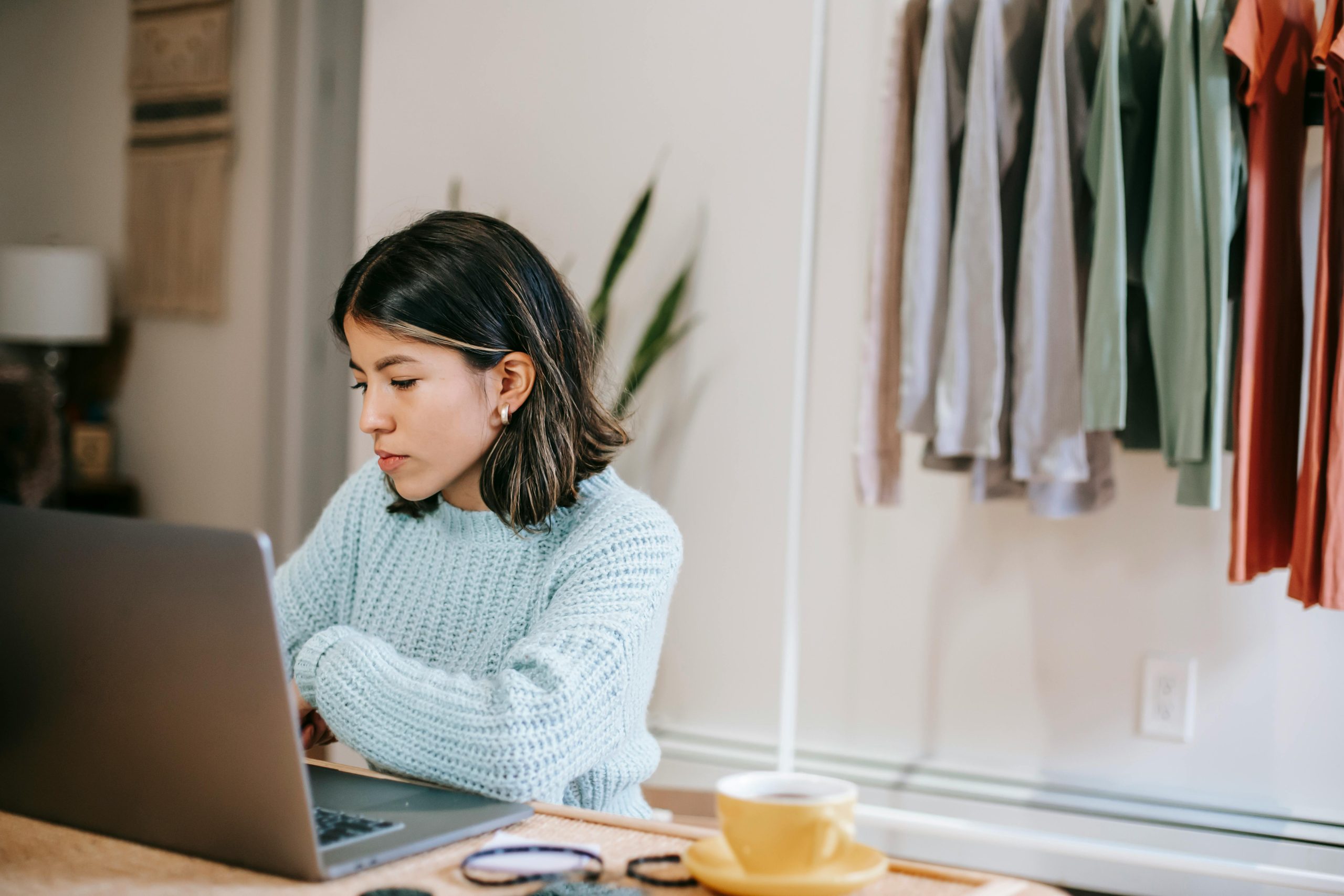 A professional woman sitting at a computer with clothing behind her