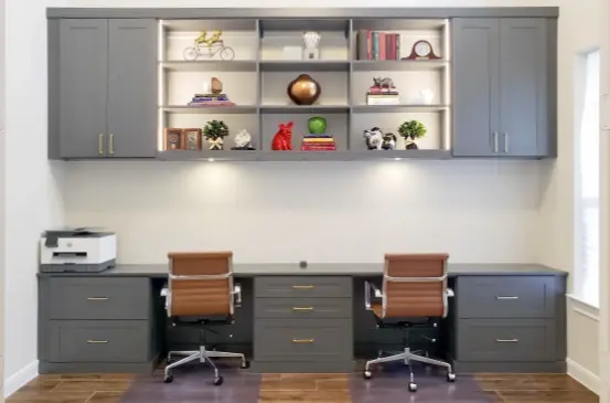 Custom home office featuring dual workstations, built-in cabinetry, shelving, and decorative display storage.
