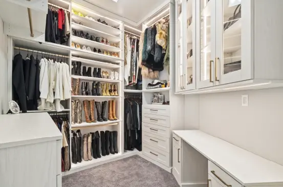 Spacious custom master walk-in closet with built-in shelving, drawers, glass cabinets, and center storage island.